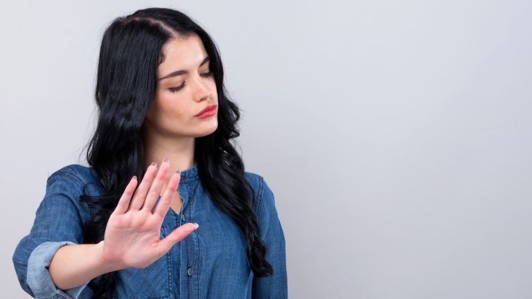 Young woman making a rejection pose on a gray background
