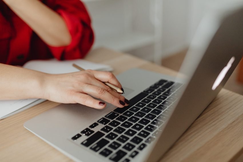 female typing on laptop with pencil in her hand.